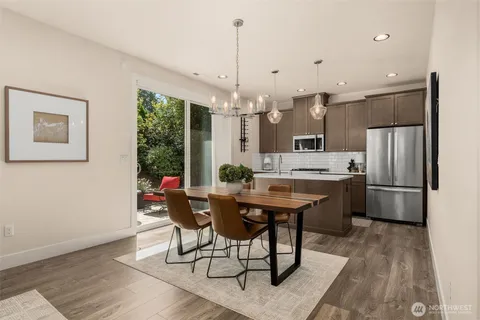 a kitchen with stainless steel appliances a dining table chairs a refrigerator and cabinets