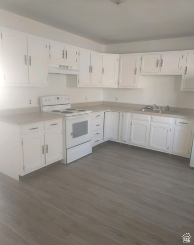 590 Pilot Avenue Wendover, UT 84083 - Photo 13 of 20 Kitchen featuring white range with electric cooktop, white cabinets, dark wood finished floors, light countertops, and under cabinet range hood