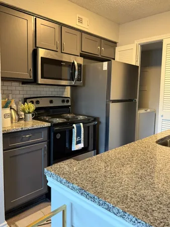 a kitchen with granite countertop a sink cabinets and wooden floor