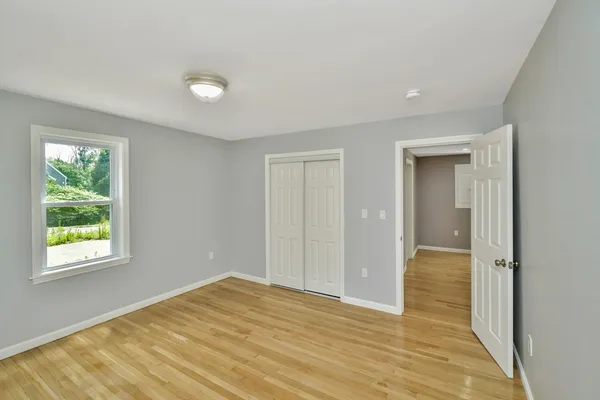 a view of hallway with a window and wooden floor