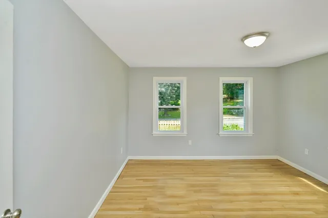 a view of an empty room with wooden floor and window
