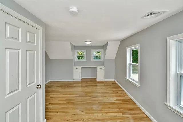 a view of a hallway to room with wooden floor and windows