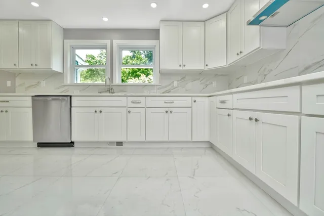 a kitchen with granite countertop white cabinets white appliances and a window