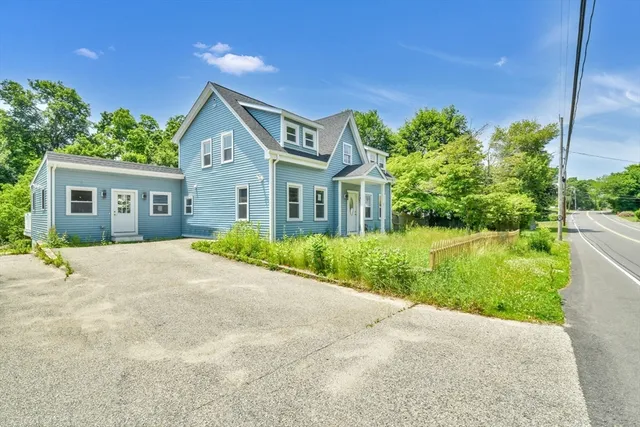 a front view of a house with a yard and potted plants
