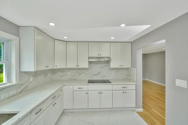 a kitchen with white cabinets granite counter tops and a stove
