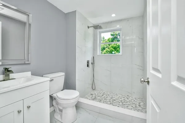 a bathroom with a granite countertop sink a toilet and shower