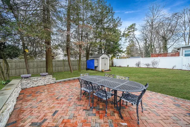 a patio with table and chairs and a big with large trees