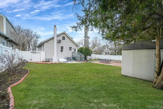 a view of a white house with a small yard and a large tree