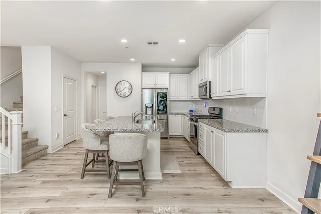 a kitchen with granite countertop a table chairs microwave and cabinets