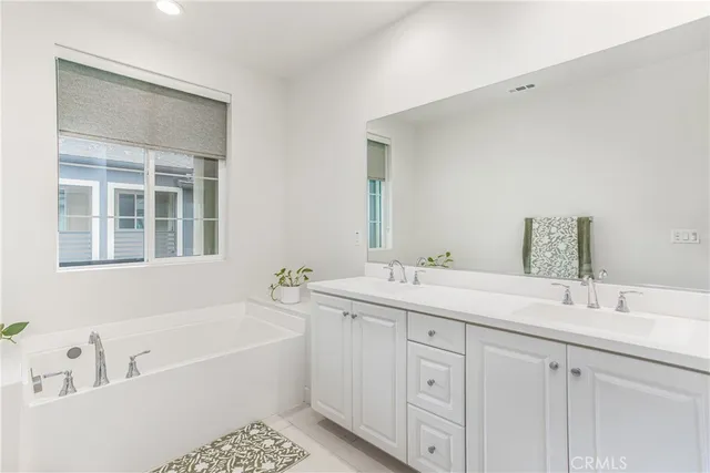 a bathroom with a tub double sink and mirror