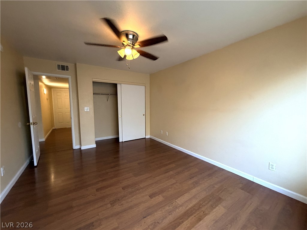 4955 South Lindell Road, Unit 203 Las Vegas, NV 89118 - Photo 15 of 31 Rich hardwood floors complement a spacious bedroom featuring a practical closet and ceiling fan.