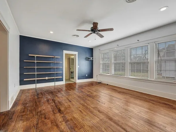 a view of an empty room with a window and wooden floor