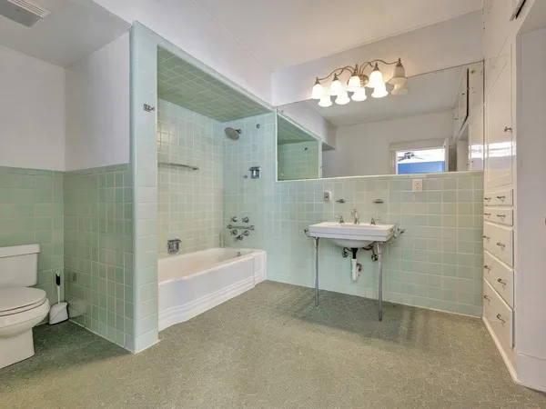 a bathroom with a sink a toilet a mirror and bathtub