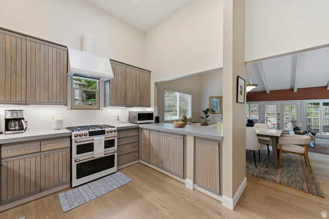 3674 Oak Rim Way Salt Lake City, UT 84109 - Photo 13 of 47 Vaulted ceiling kitchen with wood-finish cabinetry, light countertops, and a built-in range with a modern vent hood