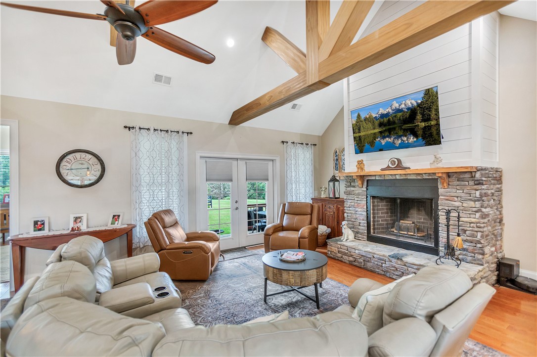1204 Cherokee Road Townville, SC 29689 - Photo 10 of 44 A cozy living space features vaulted ceilings with exposed beams, a stone fireplace, and access to the outdoors.