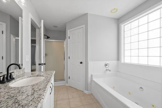 a bathroom with a granite countertop tub sink and mirror