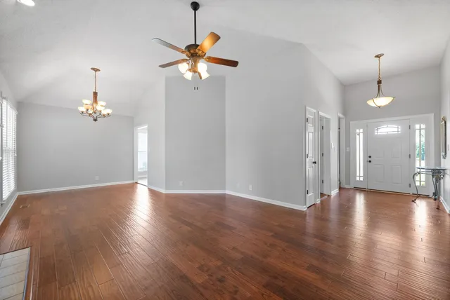 a view of an empty room with a chandelier fan