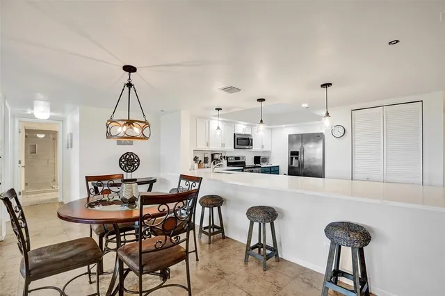 a kitchen with stainless steel appliances a dining table chairs and white cabinets