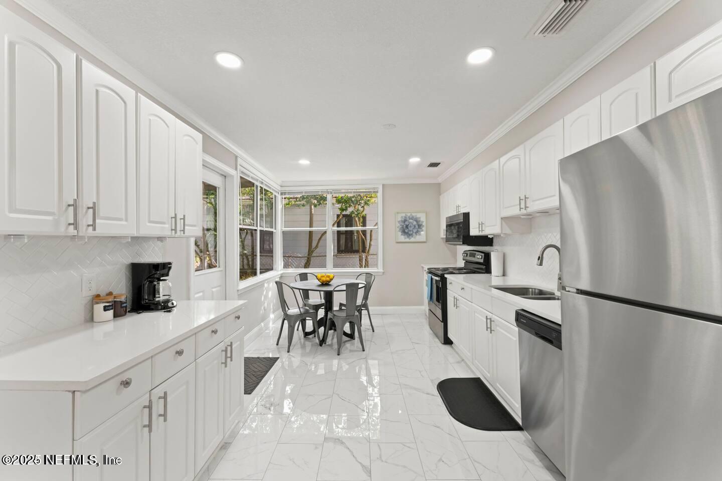 1247 Rensselaer Avenue Jacksonville, FL 32205 - Photo 16 of 24 a kitchen with white cabinets and stainless steel appliances