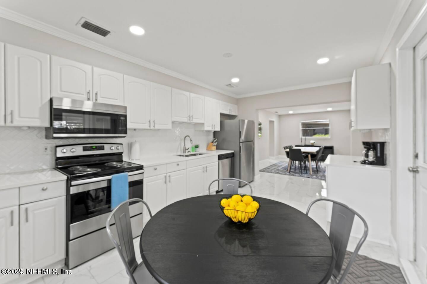 1247 Rensselaer Avenue Jacksonville, FL 32205 - Photo 17 of 24 a kitchen with a sink a stove and chairs