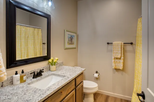 a bathroom with a granite countertop sink toilet and mirror