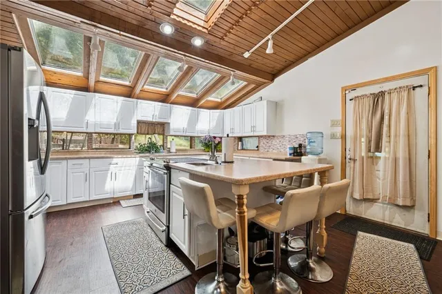 a kitchen with stainless steel appliances granite countertop a sink a counter space and a refrigerator