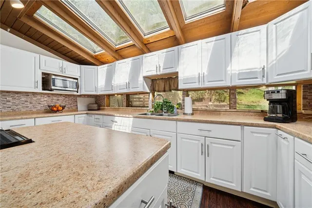 a kitchen with stainless steel appliances granite countertop a sink a stove and cabinets