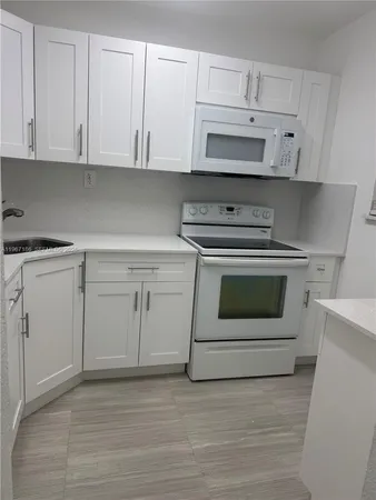 a kitchen with white cabinets and appliances