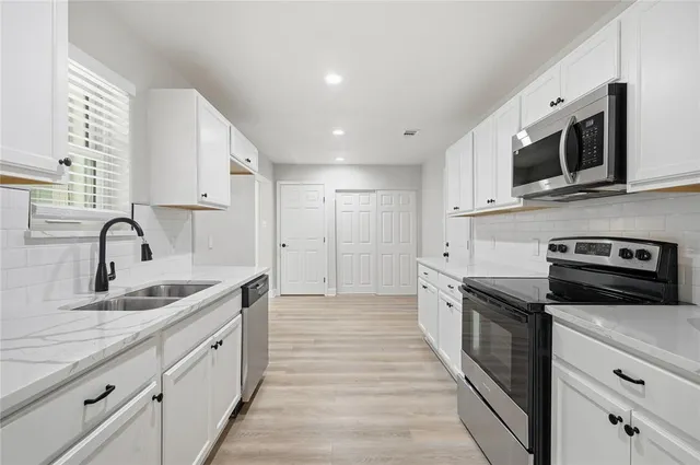 a large kitchen with stainless steel appliances granite countertop a sink and a stove
