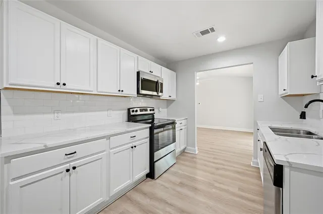 a kitchen with granite countertop white cabinets and white appliances