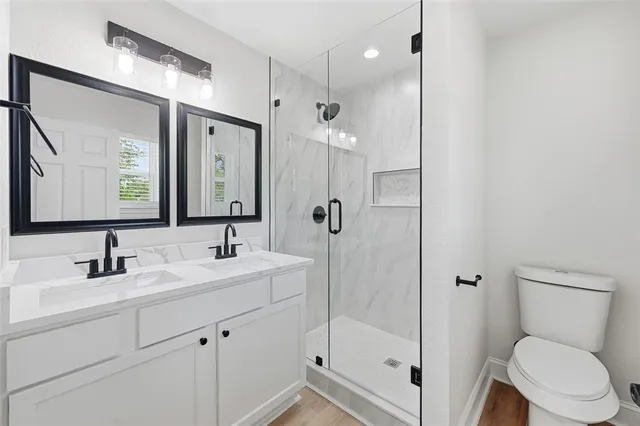 a bathroom with a sink a toilet a mirror and shower