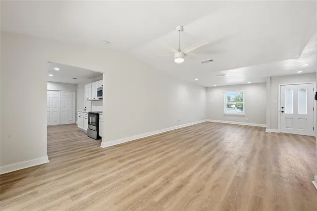 an empty room with wooden floor and windows