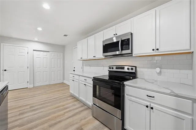a kitchen with stainless steel appliances granite countertop white cabinets a sink and dishwasher