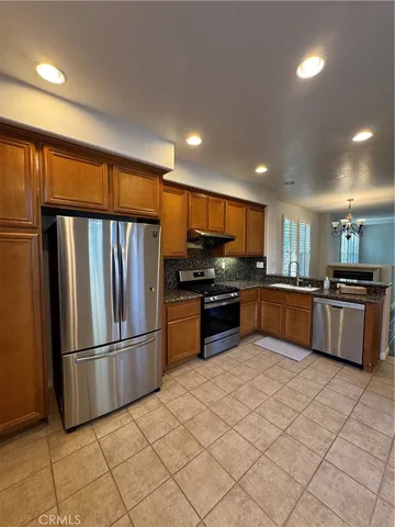 a kitchen with stainless steel appliances kitchen island granite countertop a refrigerator and a sink