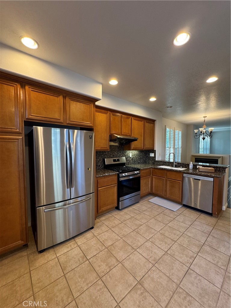 211 Tall Oak Irvine, CA 92603 - Photo 7 of 12 a kitchen with stainless steel appliances kitchen island granite countertop a refrigerator and a sink