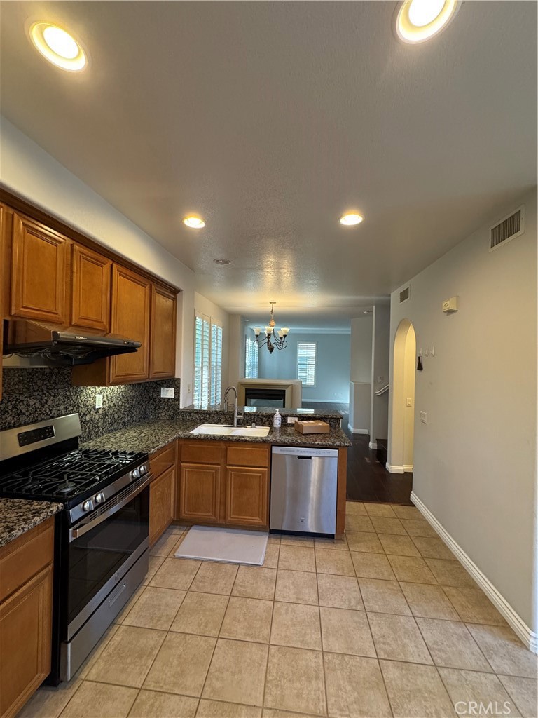 211 Tall Oak Irvine, CA 92603 - Photo 8 of 12 a kitchen with stainless steel appliances granite countertop a stove top oven a sink dishwasher and a refrigerator