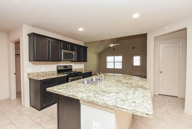 a kitchen with kitchen island granite countertop a sink stove and refrigerator