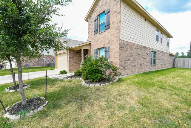 a view of a house with a yard and a large tree