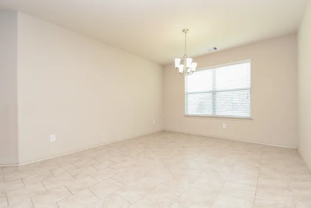 an empty room with windows and chandelier fan