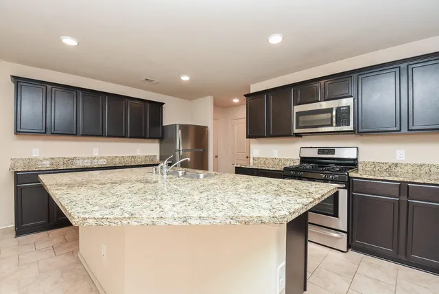 a kitchen with stainless steel appliances granite countertop a stove microwave and sink