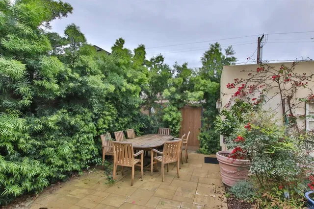 a backyard with table and chairs potted plants