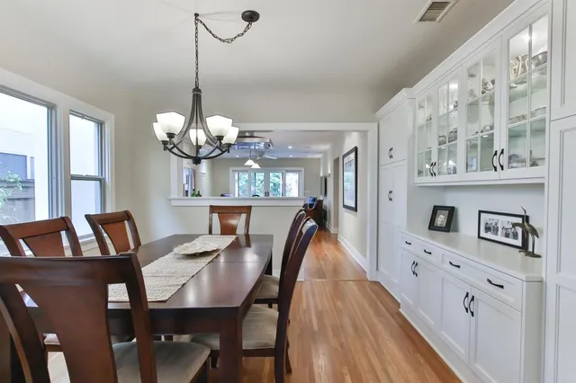 a dining room with wooden floor a chandelier a wooden table and chairs