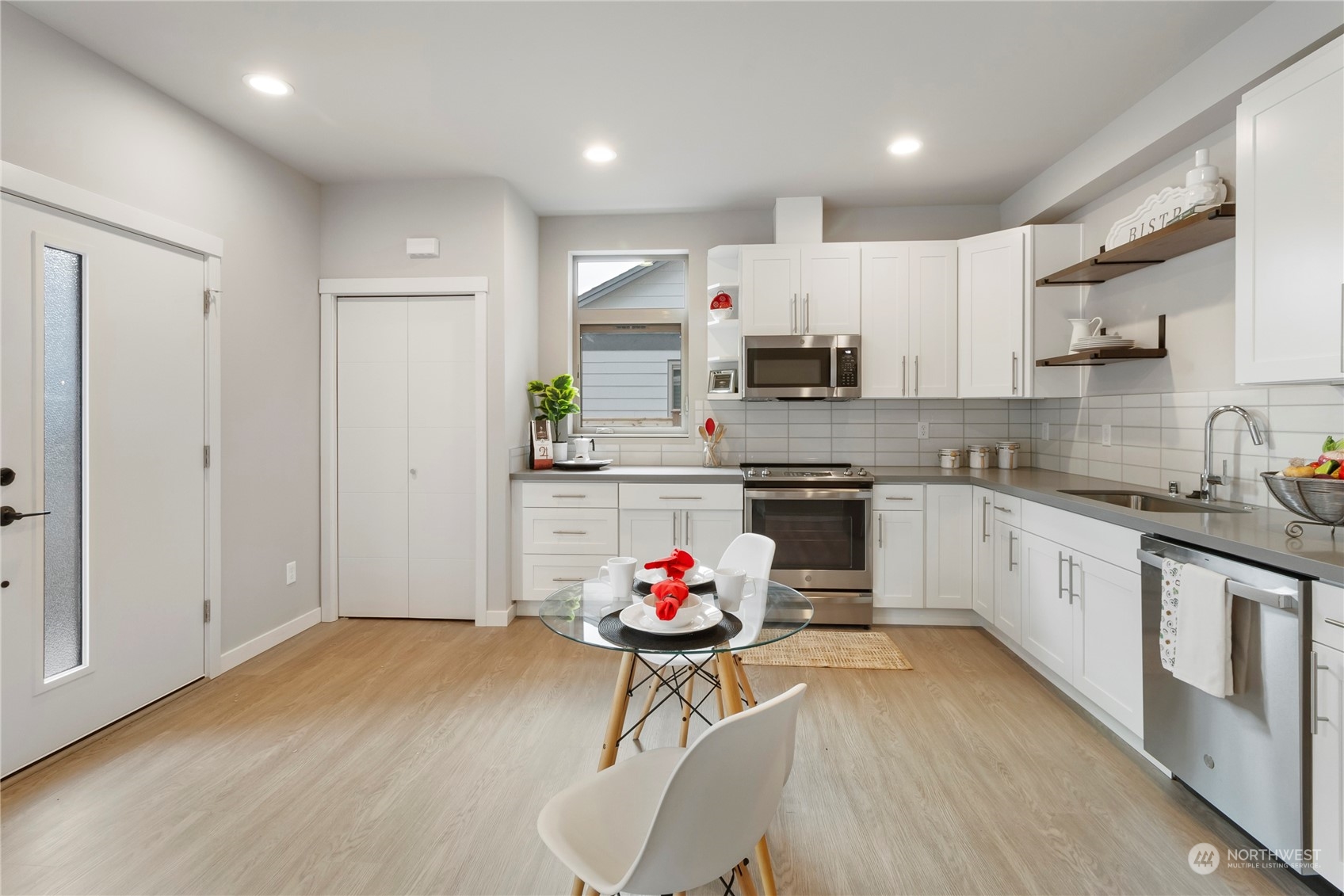 8410 17th Avenue Southwest, Unit B Seattle, WA 98106 - Photo 3 of 18 a kitchen with stainless steel appliances granite countertop a stove top oven a sink and white cabinets with wooden floor