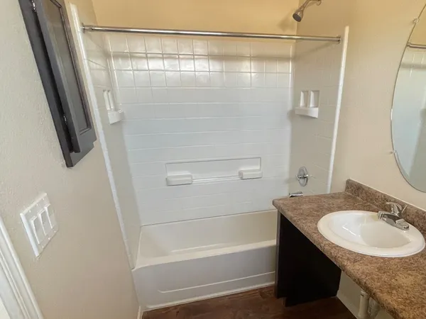 a bathroom with a granite countertop sink a mirror and a bathtub