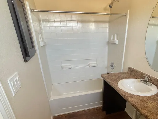 a bathroom with a granite countertop sink a mirror and a bathtub