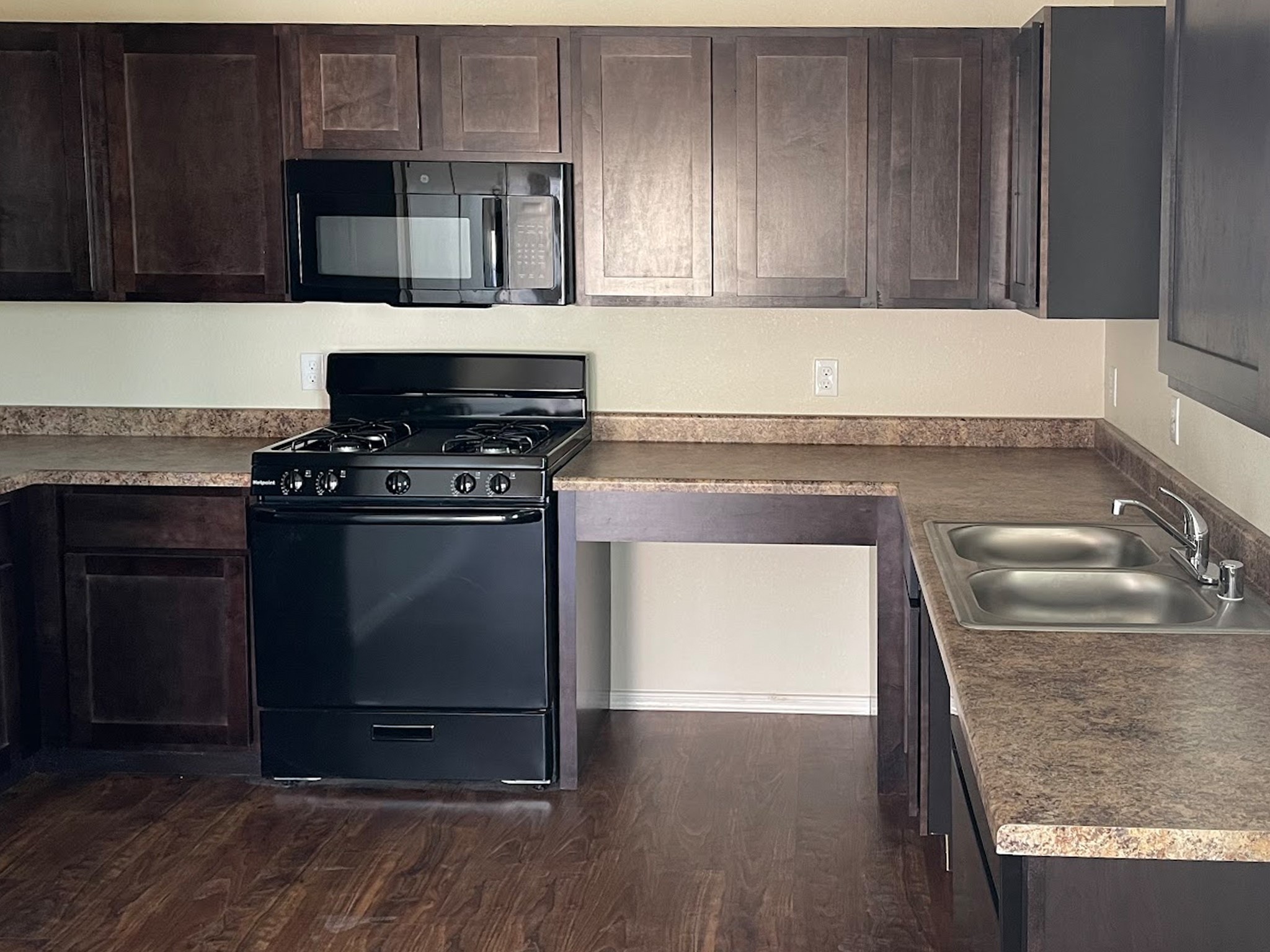 1104 Lechuguilla, Unit 49 Alpine, TX 79830 - Photo 6 of 6 a kitchen with granite countertop a stove a microwave and wooden cabinets