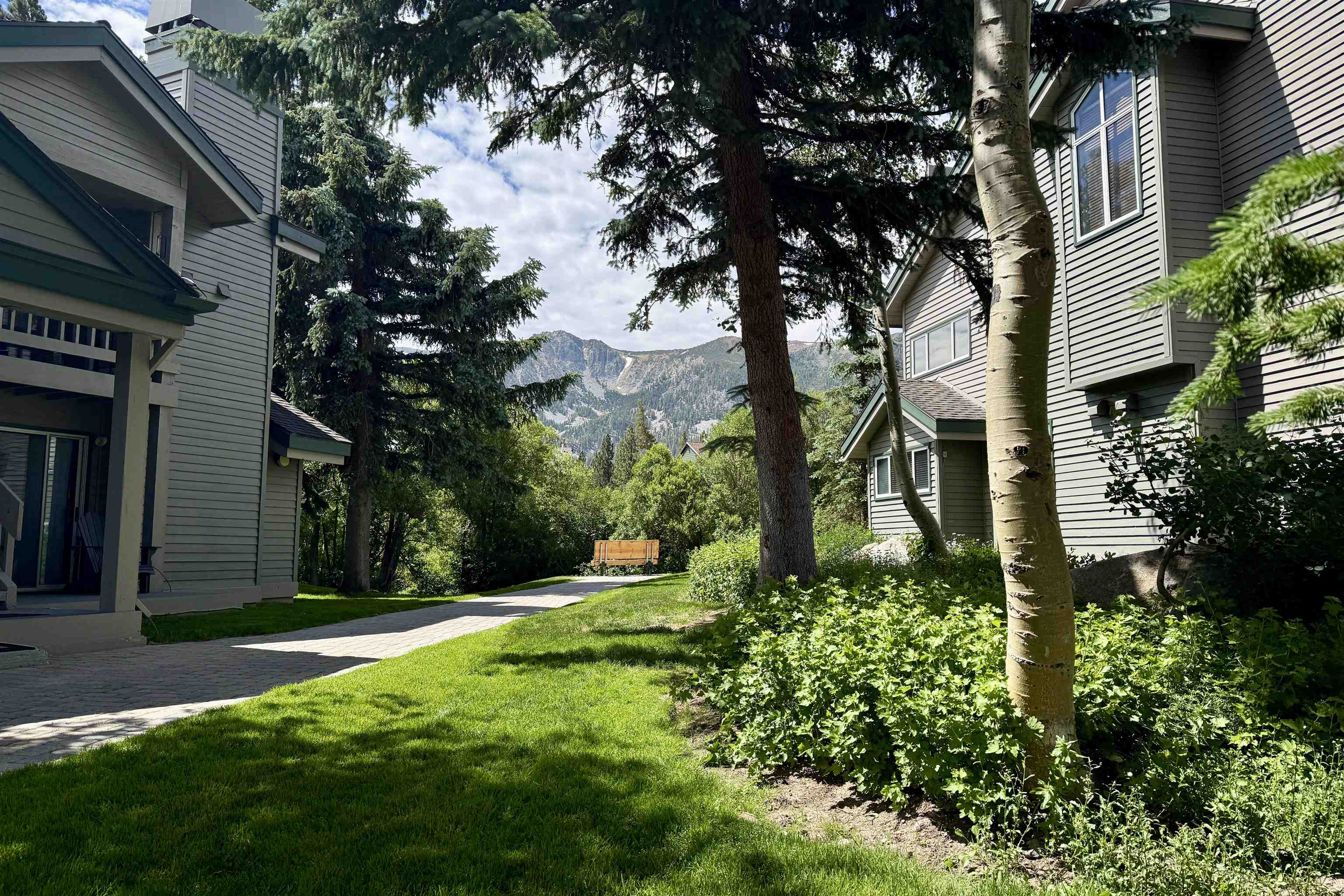 625 Golden Creek Road, Unit 625 Mammoth Lakes, CA 93546 - Photo 35 of 37 Lush green landscaping with mature trees surrounding two-story properties featuring horizontal siding and dark trim