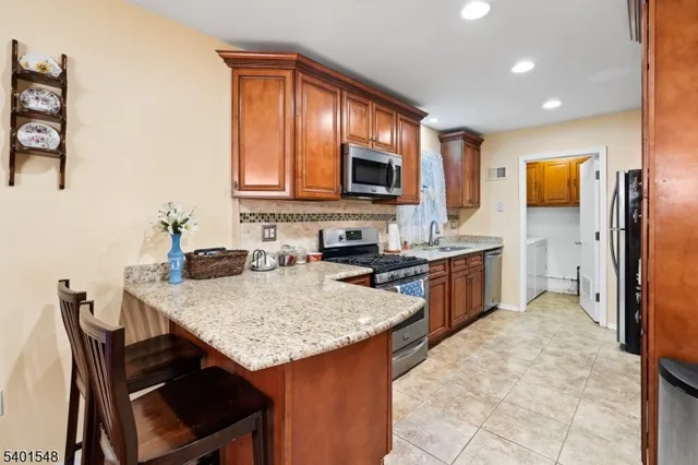 a kitchen with a stove a sink a microwave a refrigerator a kitchen island and chairs