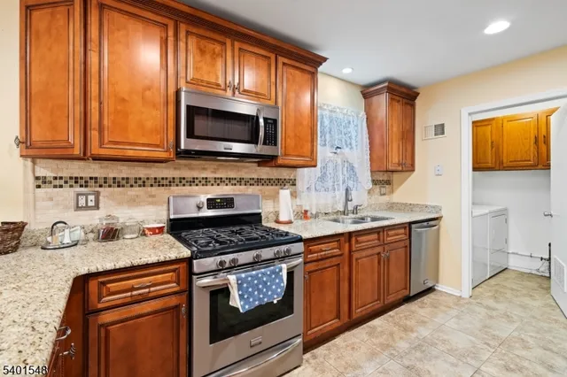 a kitchen with stainless steel appliances granite countertop a stove a sink and a microwave