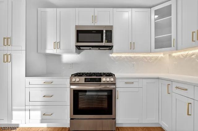 a kitchen with stainless steel appliances white cabinets and a stove top oven